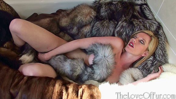Holly Kiss relaxes in a bath full of fur coats and stoles